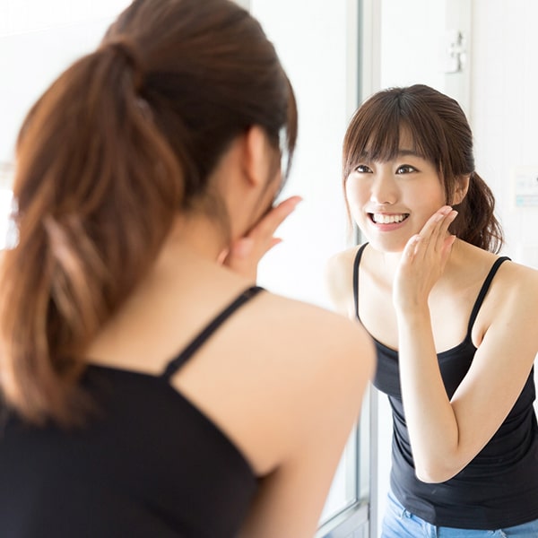 A young woman looking in the mirror after her new smile