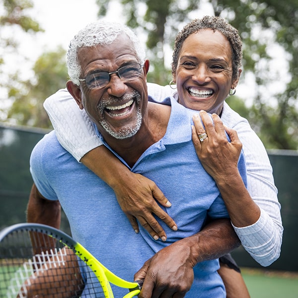 A mature couple smiling while playing tennis